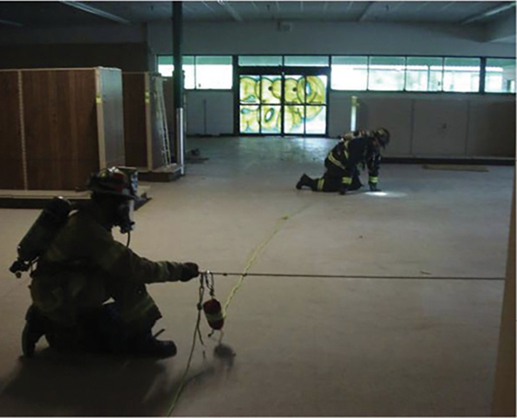 Firefighters practice search rope skills in an empty box store setting