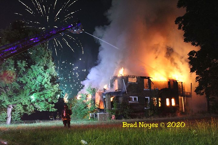 Detroit fire crews at scene of fire with fireworks above