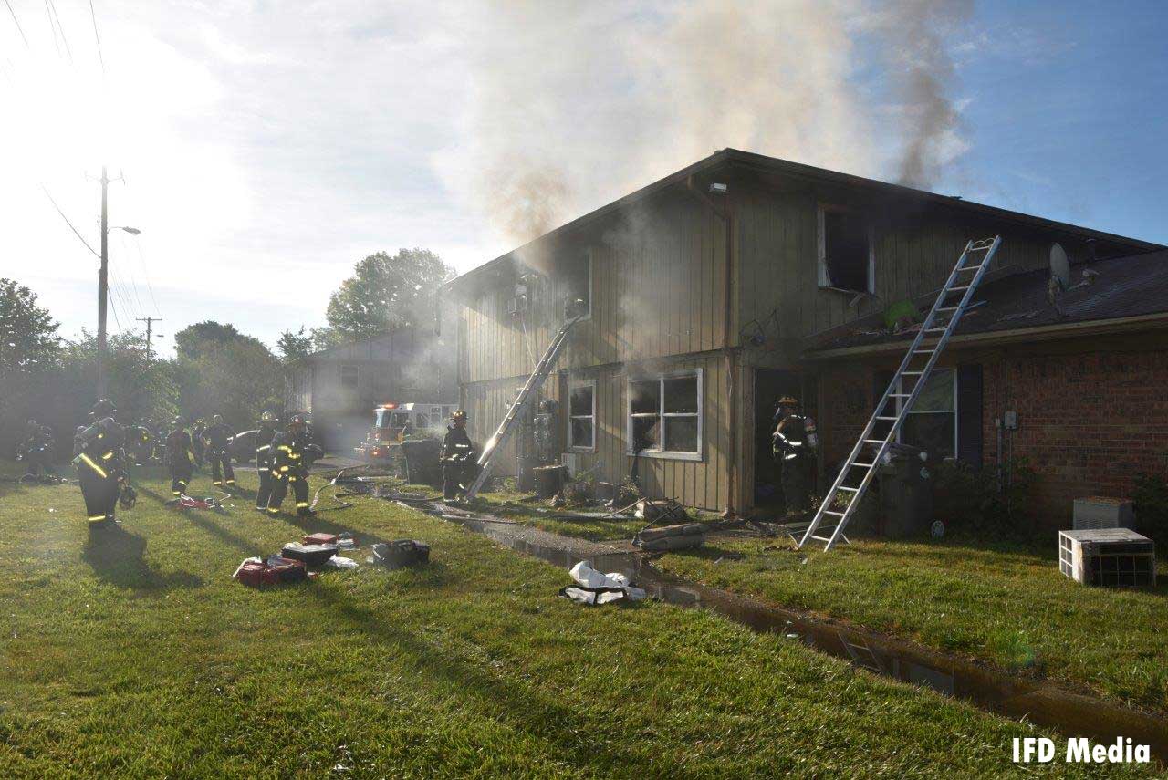 Firefighters and ladders at the scene of the fire with smoke condition