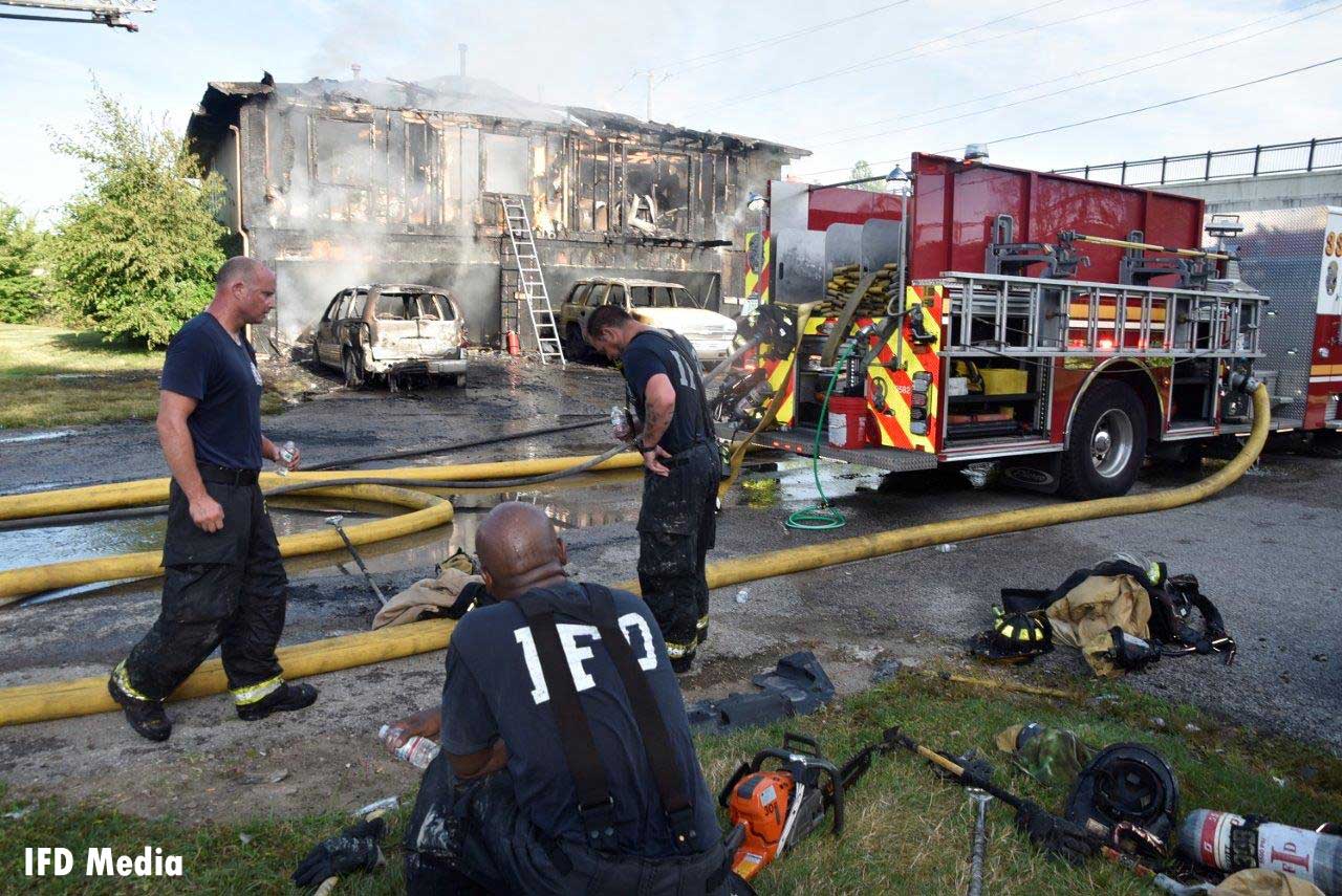 Firefighters rehab with a fire truck at the scene of the fire