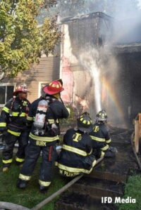 Firefighters conduct a hosestream on the apartment's exterior