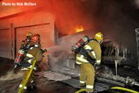 LAFD crews with a hoseline gain access to garage