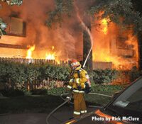 Firefighter applies water to the flames