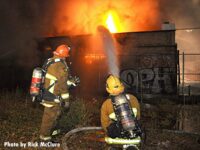 Firefighters with a hoseline putting water on flames