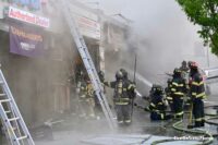 Firefighters with a ladder outside a smoky business