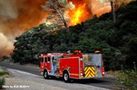 Fire truck with wildfire raging in background