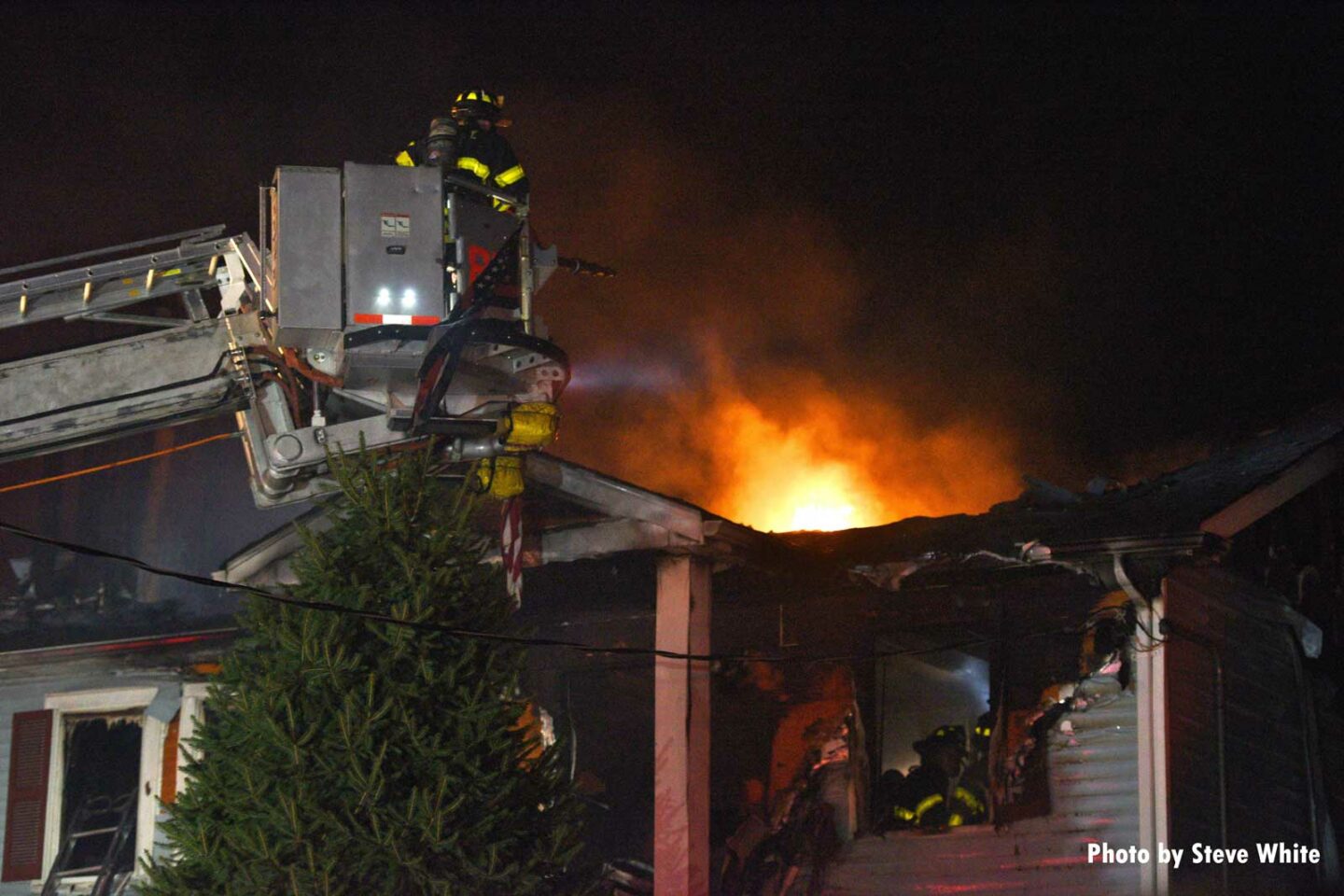 FDNY Tower Ladder with fire showing from roof of dwelling