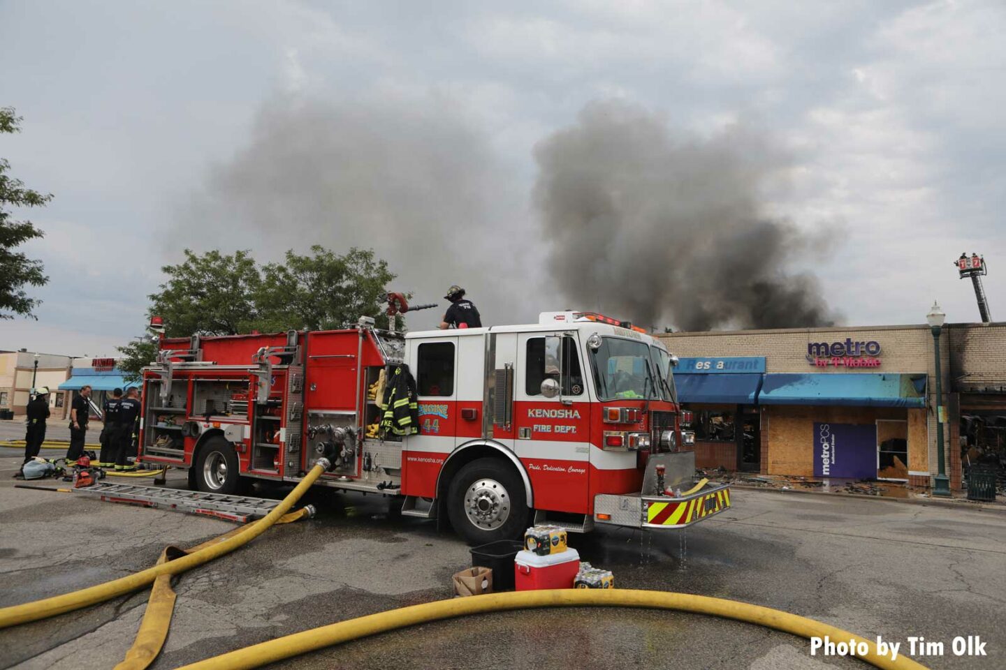 Fire apparatus with supply lines and smoke rising in the background