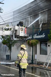 Firefighter in tower ladder aims stream into the building