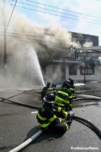 Firefighters on a line direct a stream a the building