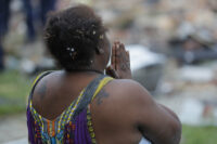 A woman stands in front of a pile of debris