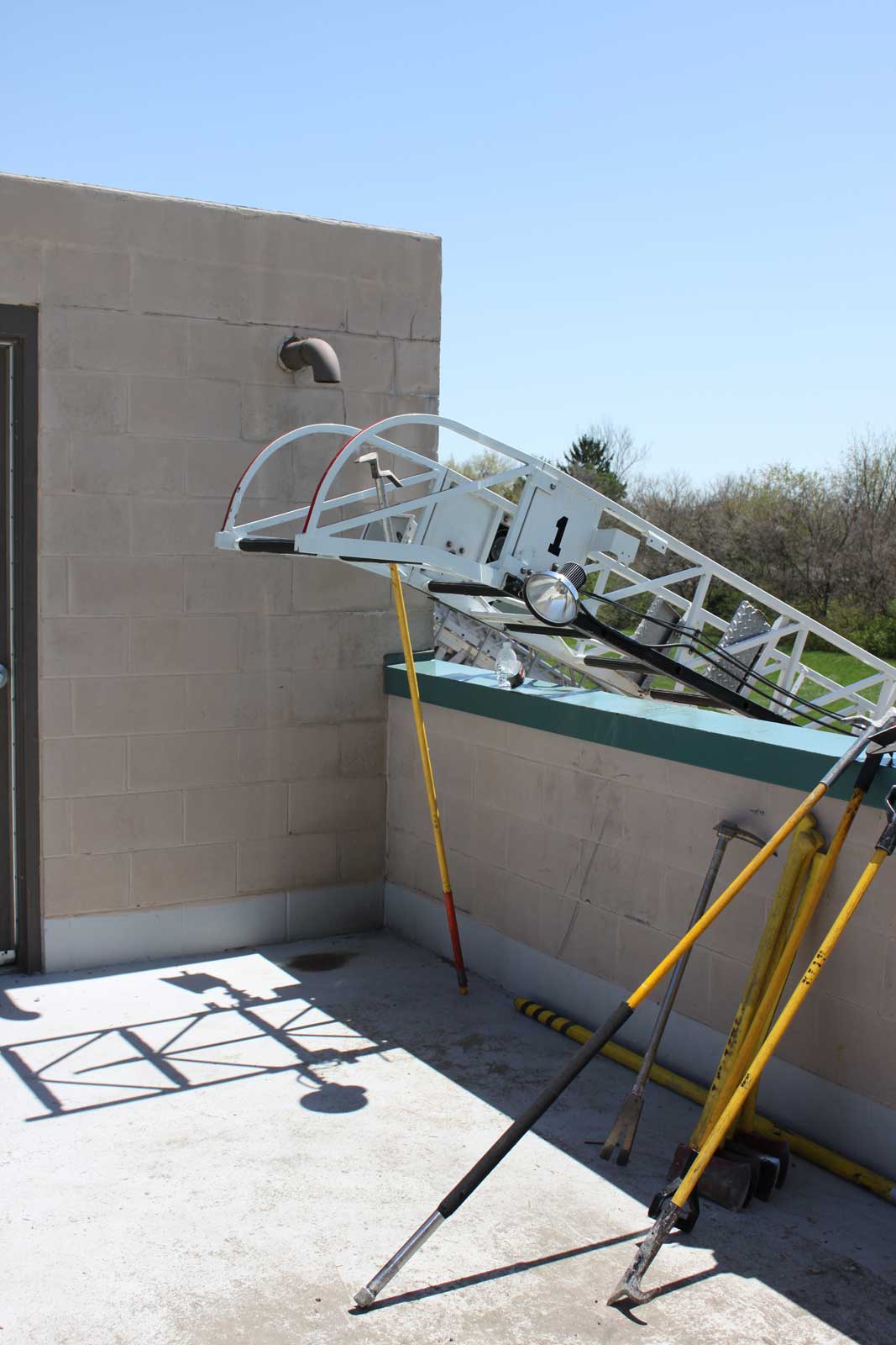 Aerial tip extending over parapet wall onto flat roof with firefighter tools