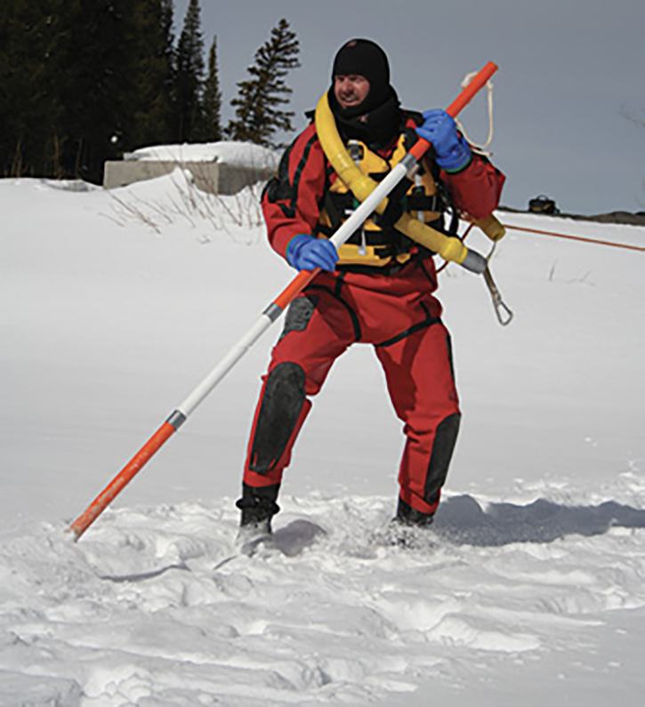 A swiftwater dry suit is shown here with a flotation sling and an ice rescue pole.