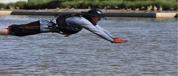 In an offensive water entry, the rescue swimmer places his hands in front to break up the water and protect his face as he makes entry. It allows the swimmer to keep his head up and out of the water on contact with the water and keep his eyes on the victim. Notice also his body is flat, to minimize his impact on the water and to avoid injury when entering the water.