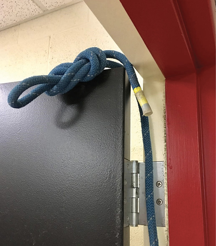 Place a rope with an end knot over the top of the door and beyond the hinge.