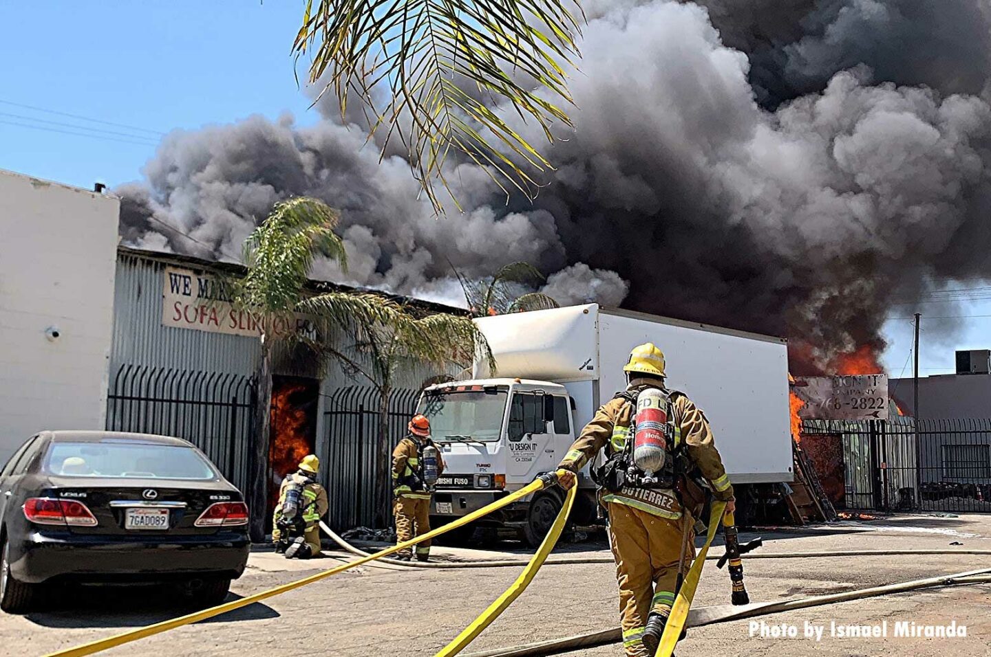 LAFD firefighters drag hoselines towards building with smoke showing