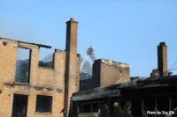 Firefighter on a ladder behind burned out buildings