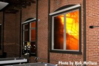 A firefighter with flames seen in the window