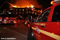 Fire vehicle parked in front of raging fire in housing complex