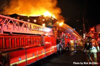 Ladder truck with flames shooting from the building