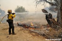 A firefighter applies water on the flames