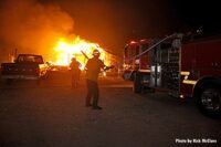 Firefighters and an apparatus as flames from Bobcat Fire rage in the background