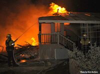 Flames consume a building as firefighter applies water