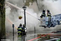 Firefighters on the ground and in a bucket aiming hose streams