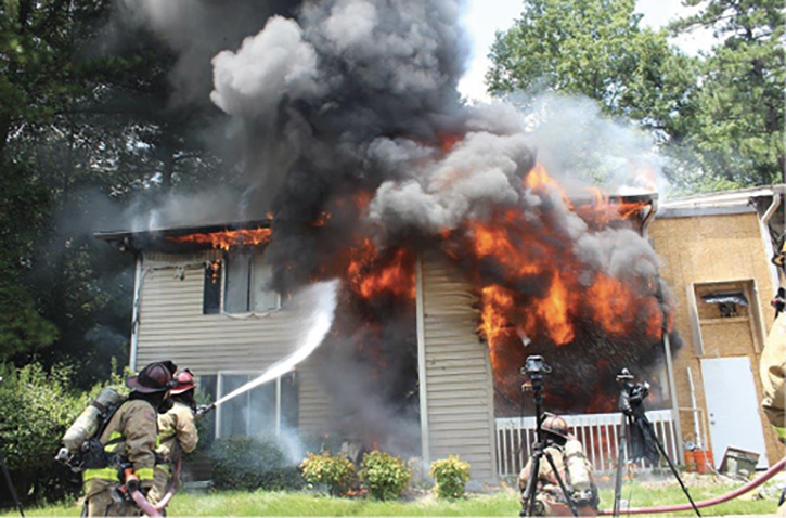 Firefighter applying exterior stream on structure