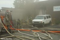 Firefighters maneuvering into fire building amid hoselines