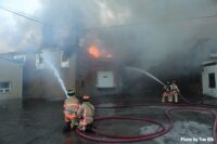 Two pairs of firefighters with hose streams on building