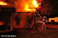 LAFD firefighter applies water on flames shooting from a home