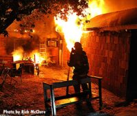 Firefighter silhouette against flames raging inside a home