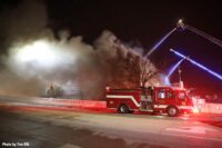 Smoke drifts across a street with fire apparatus