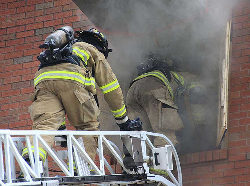 Firefighters enter a building via an aerial ladder during training at FDIC International