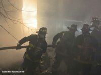 Boston firefighters haul hose at a three-alarm fire