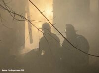 Boston firefighters framed by firelight