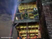 Boston firefighters on the charred deck of a home