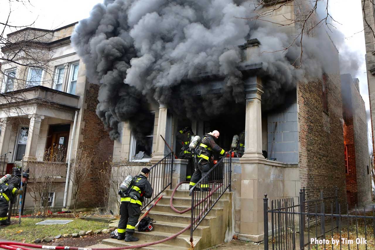 Smoke shoots from a building as Chicago firefighters make entry