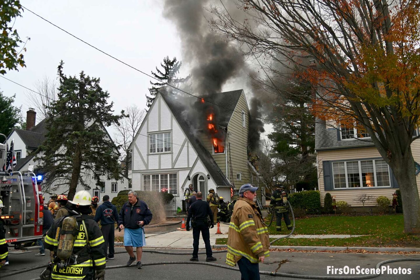 Flames shoot from the second floor of a home as firefirefighters work