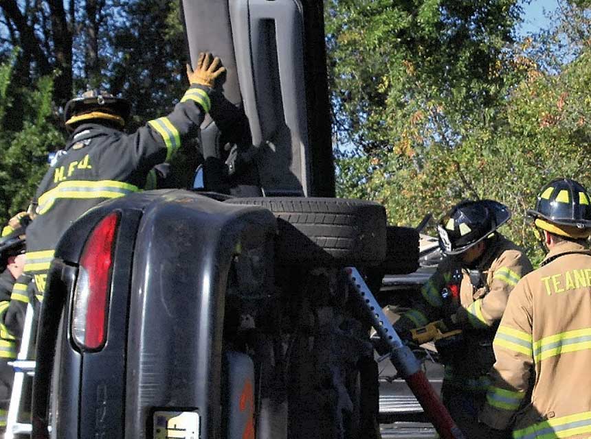 Firefighters perform vehicle extrication on a vehicle on its side