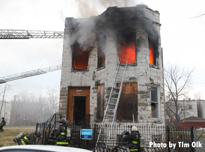 Firefighters battle flames at a vacant building in Chicago with ladder at front of home