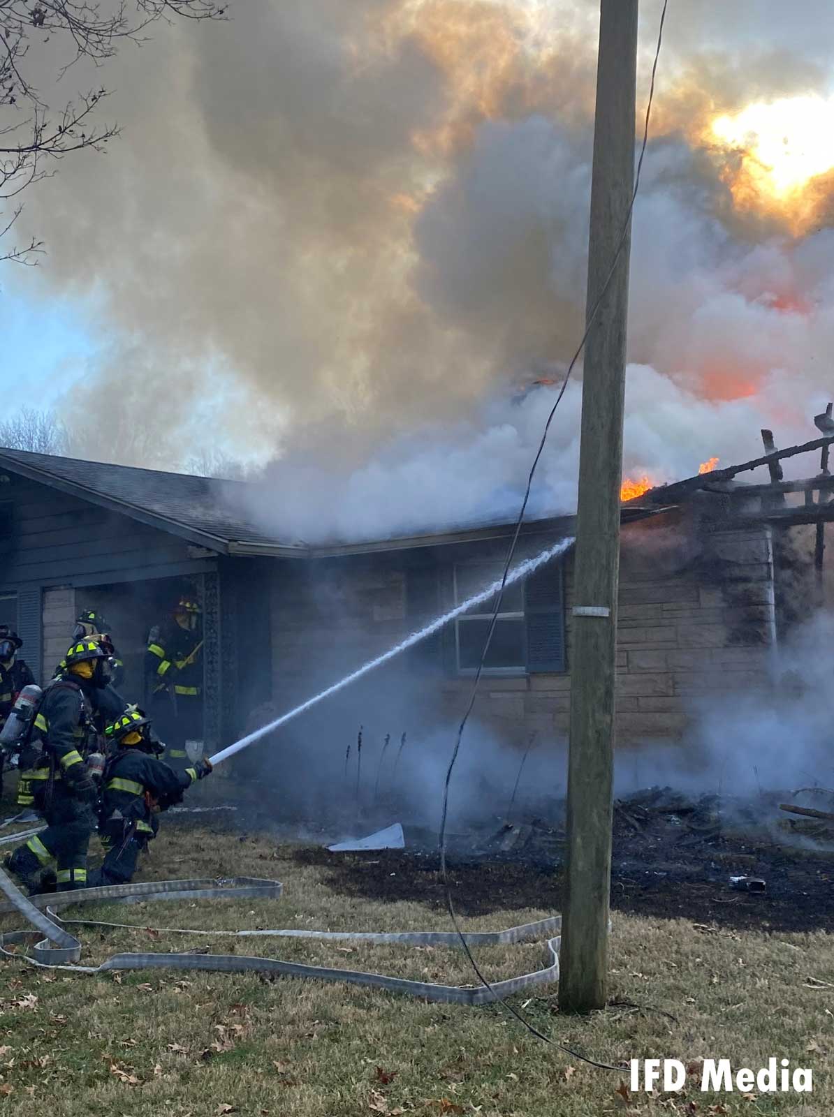 FIrefighters apply a hose stream to the fire from the outside