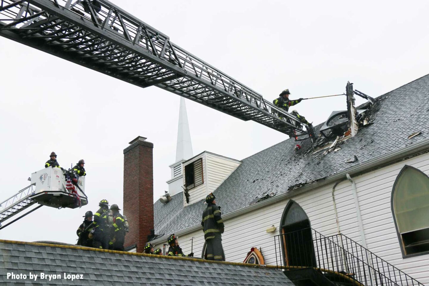 Aerial device extended to roof of church with firefighter working