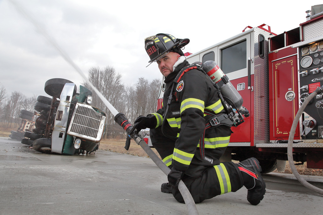 Firefighter in gear with an apparatus flowing water