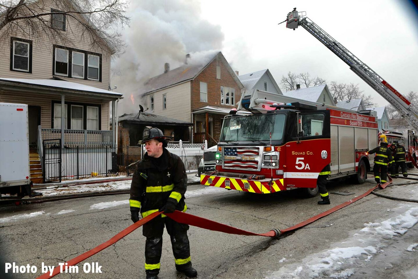 Chicago firefighter holding an LDH supply line at a house fire with Squad 5