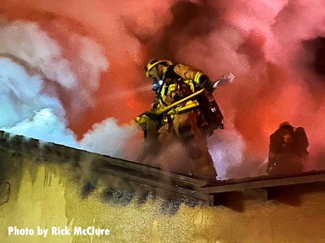 A firefighter on the roof at a Los Angeles house fire