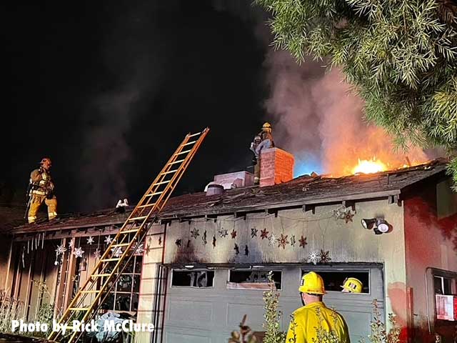 Firefighters on the roof with fire showing