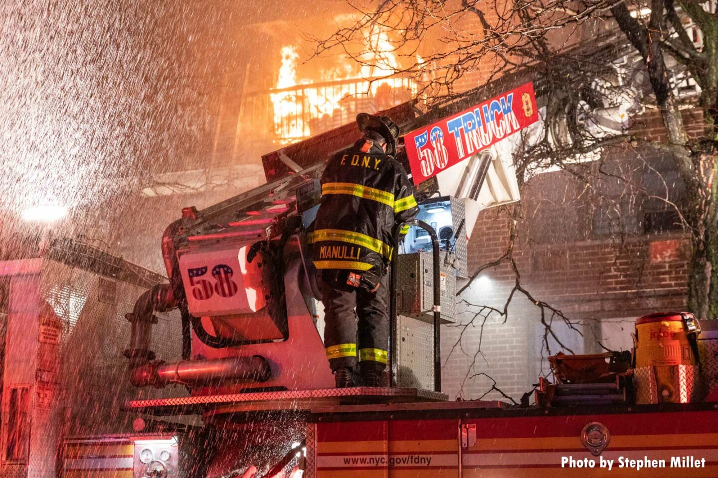 Flames rage in a building as a firefighter on 58 Truck works. This Bronx fire was the first multiple-alarm of 2021 for the FDNY