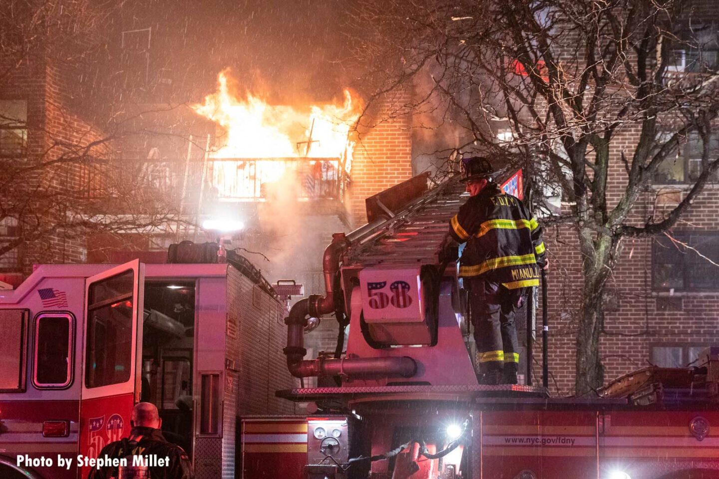 Flames rage behind a firefighter working on Truck 58 in the Bronx